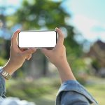 Over shoulder view of asian male tourist taking photo with smart